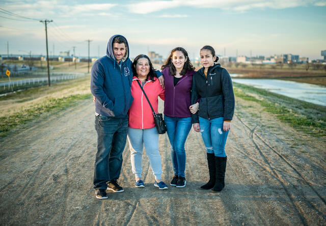 four people standing together on a road