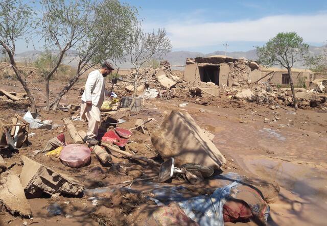 A man walks trough rubble in a destroyed village