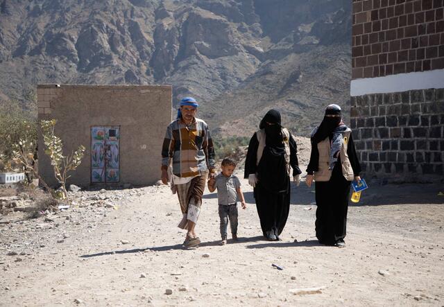 three adults and one child walking the road