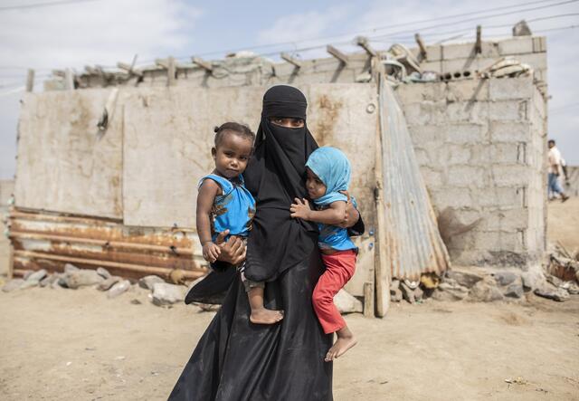 A veiled mother with her two young children