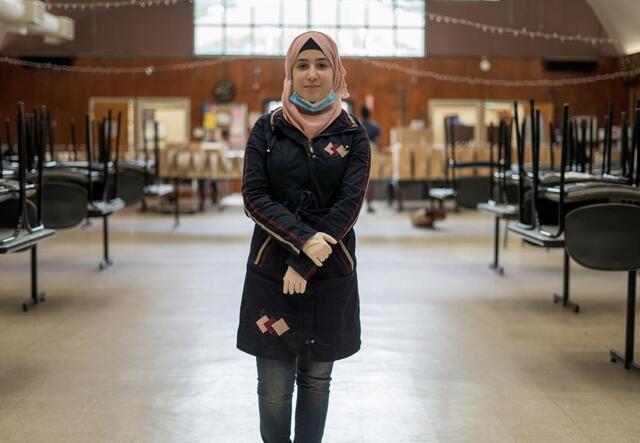 Rania Abou stands in world central kitchen wearing gloves and a mask.