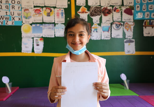 Joumana holding her schoolwork towards the camera