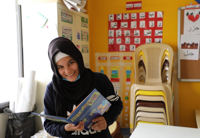 Widad holding her schoolbook at the IRC-run learning centre