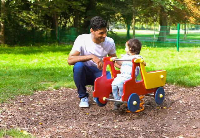 Vater mit kleiner Tochter auf dem Spielplatz