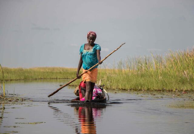 Eine Frau in Südsudan fährt mit einem Boot durch einen Sumpf.