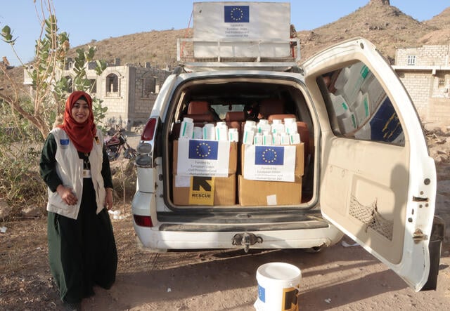 Dr. Bushra stands near an IRC mobile health van during a field visit