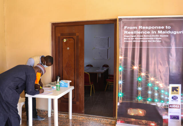 Two community members stand near the entrance to the room where EU-funded workshops take place