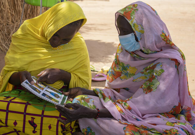 Fantaou Mallam Kiari (20) und eine andere Frau in Diffa, Niger, lesen eine IRC-Broschüre über die Prävention von Mangelernährung von Kindern. Mütter wie Fantaou erhalten von IRC Bargeldhilfe sowie wirtschaftliche Schulungen, damit sie ihre Familien unterstützen können.