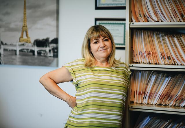 Senior Legal Representative, Nadeana Fortin, posing next to only a portion of her client files in her office.