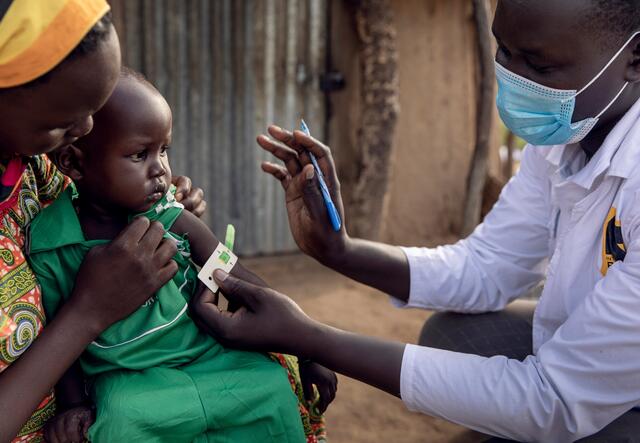 James from the IRC takes care of Peter, held by his mother, Abang, at home in Northern Bahr El Ghazal, South Sudan.