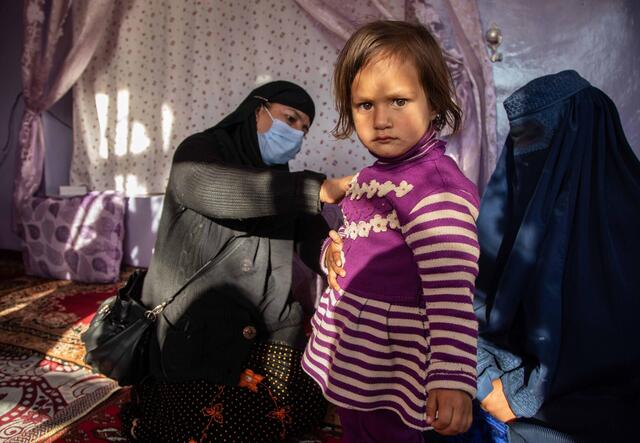 Little girl in stripy dress is given jab in Afghanistan
