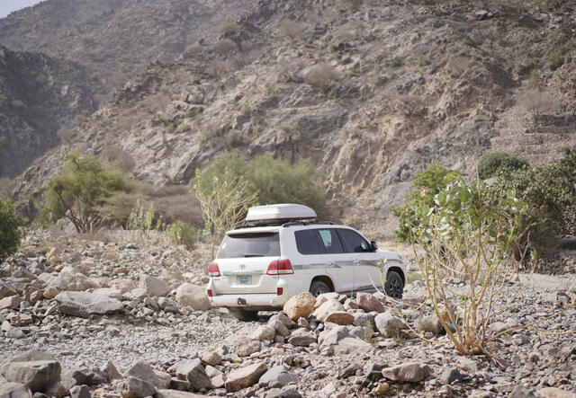 White car driving away through rocky terrain