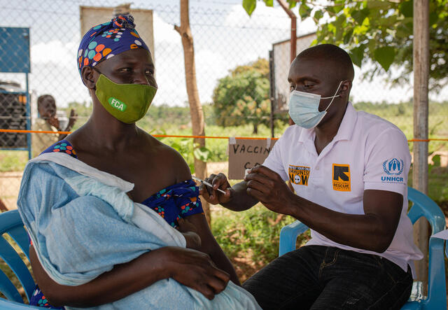 A Ugandan teacher gets the first shot of the Covid-19 vaccine by IRC health worker