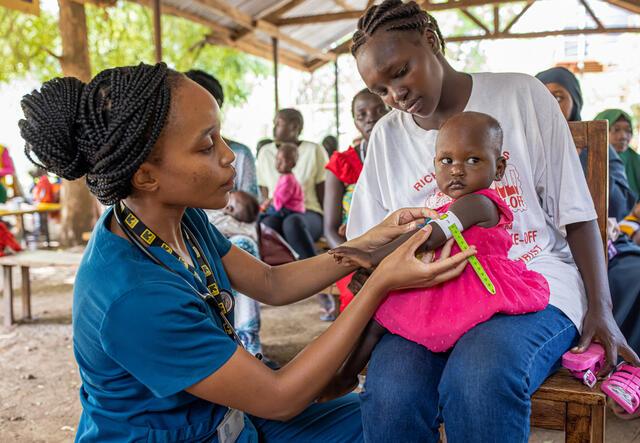 An IRC doctor treats a one year old girl who sits on her mother's lap