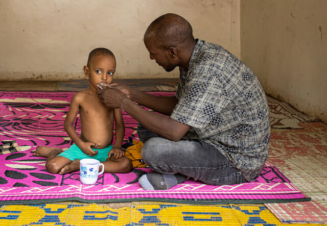 A man feeds his son during a screening for malnutrition at Locher Angamor Health Dispensary in Kakuma Refugee Camp, Turkana, Kenya.