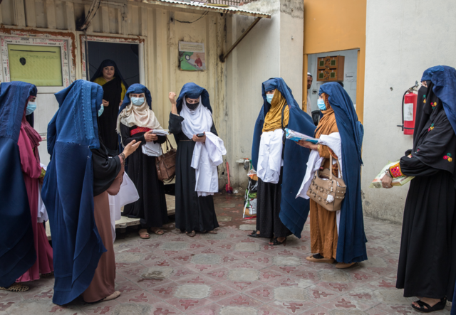 7 women, part of the mobile health team, meet in a courtyard.