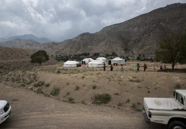 A few tents dot an otherwise barren, mountainous landscape.