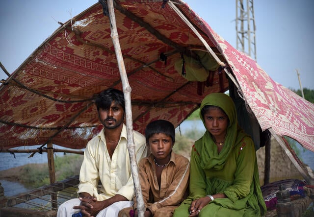 파키스탄 홍수 후 텐트 아래 앉아 있는 가족