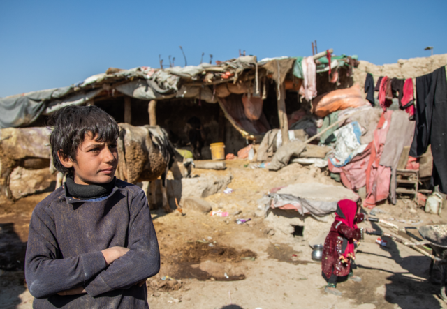 A boy, living in Ghaibi Bala camp in Kabul, Afghanistan, looks on as his mother is interviewed by IRC staff.