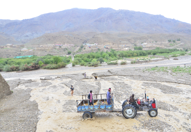 Men sit in a tractor that crosses a flooded area.