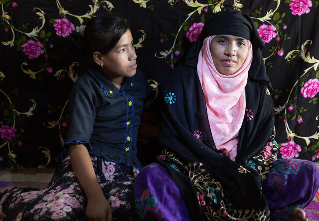 Tahera sitting with her daughter behind a bright backdrop, smiling at the camera