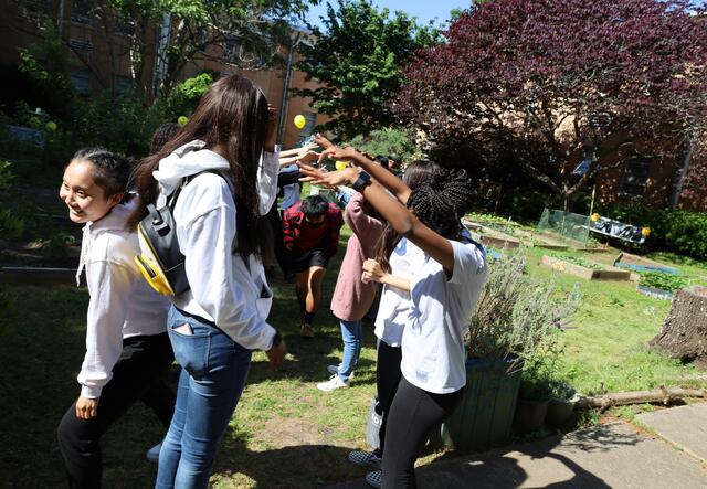 A group of high school students form a bridge with their arms for other students to run under.