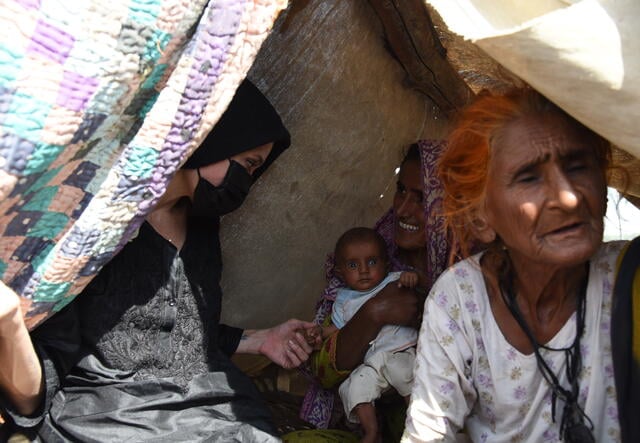 Angelina Jolie visits with a mother and her child affected by flooding.