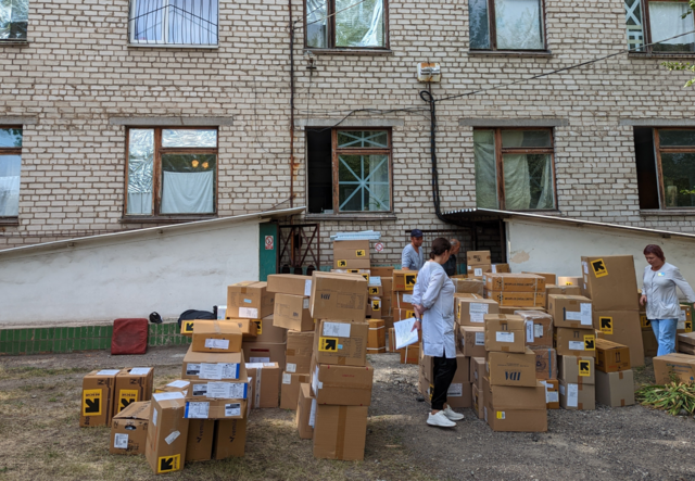 IRC staff and hospital staff are moving many IRC boxes full of helpful supplies.