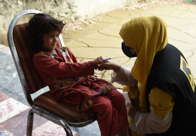 A girl shakes the hand of an IRC employee