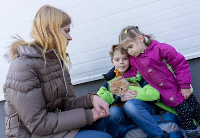 Eine Mutter sitzt mit ihrem Sohn, ihrer Tochter und der Katze der Familie zusammen.