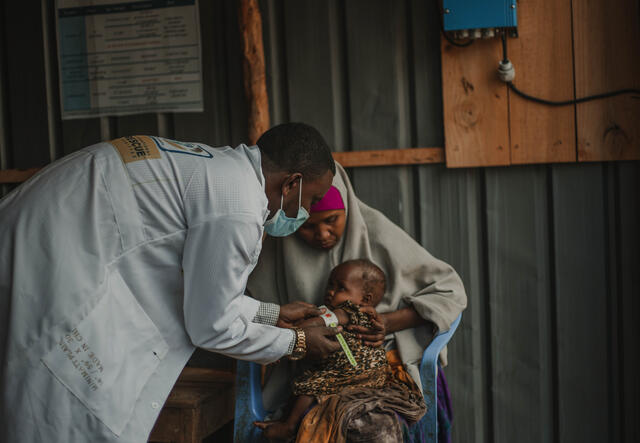 24-month baby, held by mother, receives service at Danwadag Health Centre, Somalia.