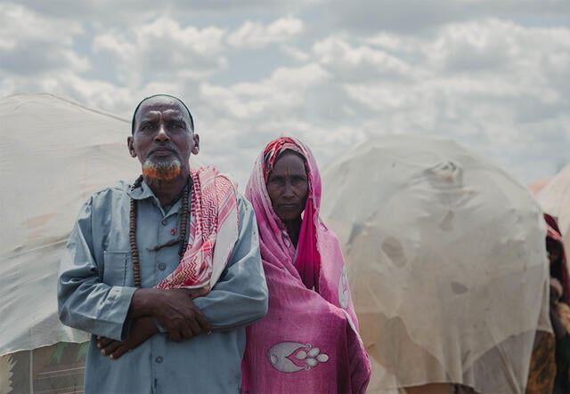 Mohamed Hassan, 71, and Madina Omar, 70, pose for a photo outside of a group of huts in Somalia.
