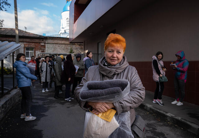 An older Ukrainian woman holding a blanket distributed by the IRC