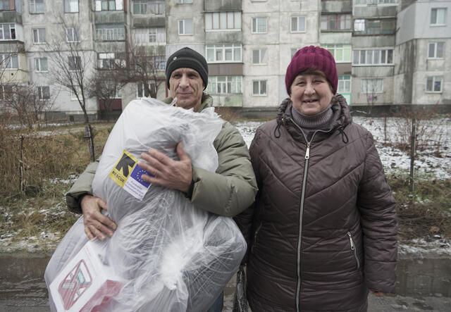 Siblings Valentyna and Alexander hold their winter kit and look at the camera 