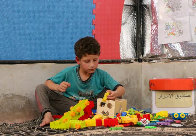 뇌위축증을 가지고 태어난 7살 시리아 소년인 테이머가 국제구조위원회의 교실에서 바닥에 앉아 장난감을 가지고 놀고 있습니다.