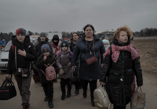 A group of Ukrainian refugees walk towards the camera near the Polish border.