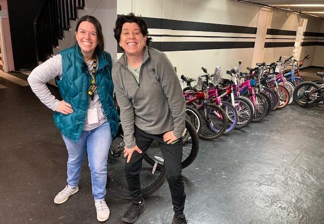 Youth Program Supervisor, Julie Goldberg, and a man from FB4K posing with a collection of bikes.
