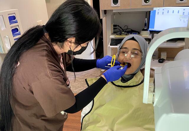 Two IET students, one in the dentist's chair and the other practicing examining her teeth.