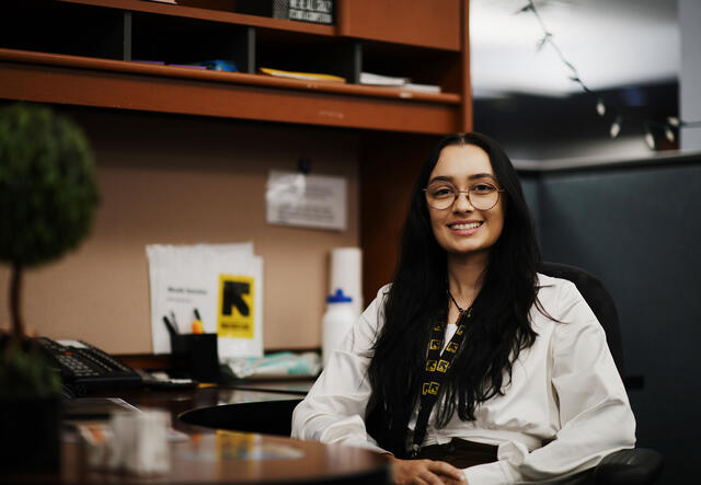 Caseworker Assistant, Nicole Sanchez, poses for photo at her desk.