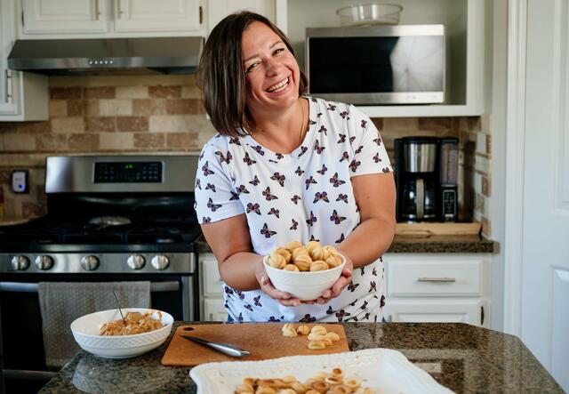 Ukrainian women in the kitchen holding a bowl of cookies.