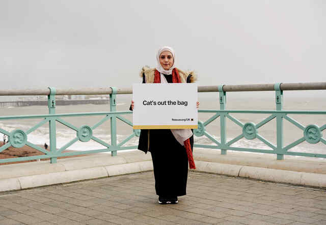 Rabab holds British Idiom sign 'Cats out the bag'