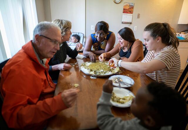 A co-sponsor family shares a meal with new arrivals.