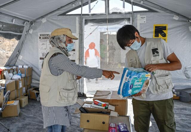 Two people sorting through supplies inside a tent