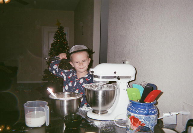 Oleskii holds a sieve over his head whilst baking
