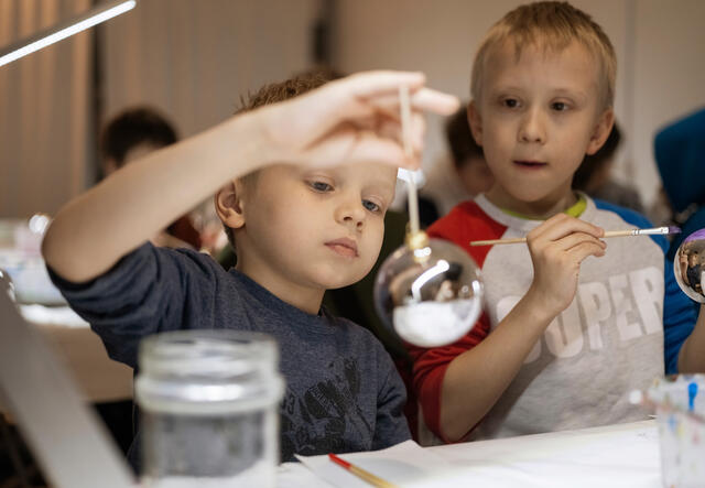 Two young boys decorate ornaments at workshop.
