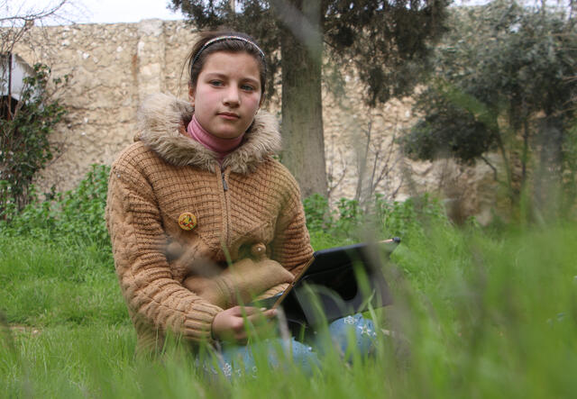 Ahlam sits by herself in a field in northern Syria.