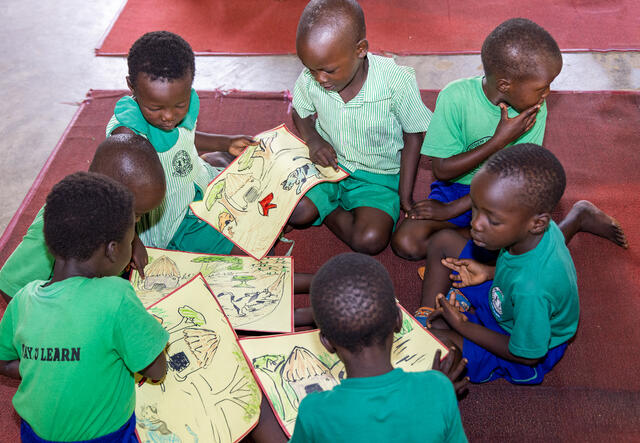 A group of young children sit in a group and work on a PlayMatters activity.