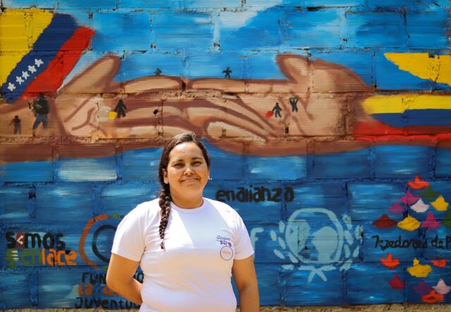 A woman, Omaira, standing in front of a painted wall