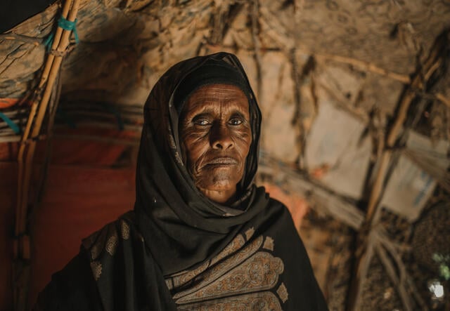 Fose poses for a portrait insides her dimly lit room in Somalia.
