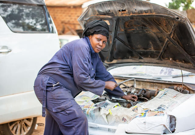 Tumusifo works on the engine of a car.